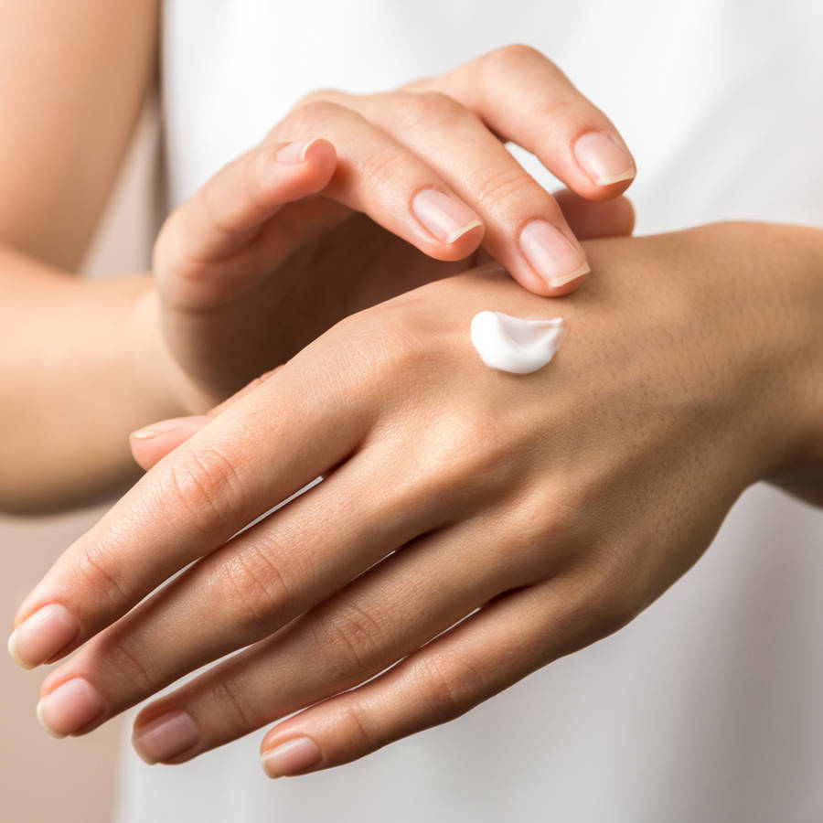 Mujer poniéndose crema de manos